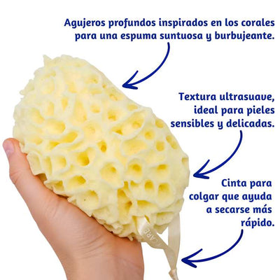 Esponja de baño 'coral scrubs' sostenida en una mano con un texto que describe sus características sobre un fondo blanco